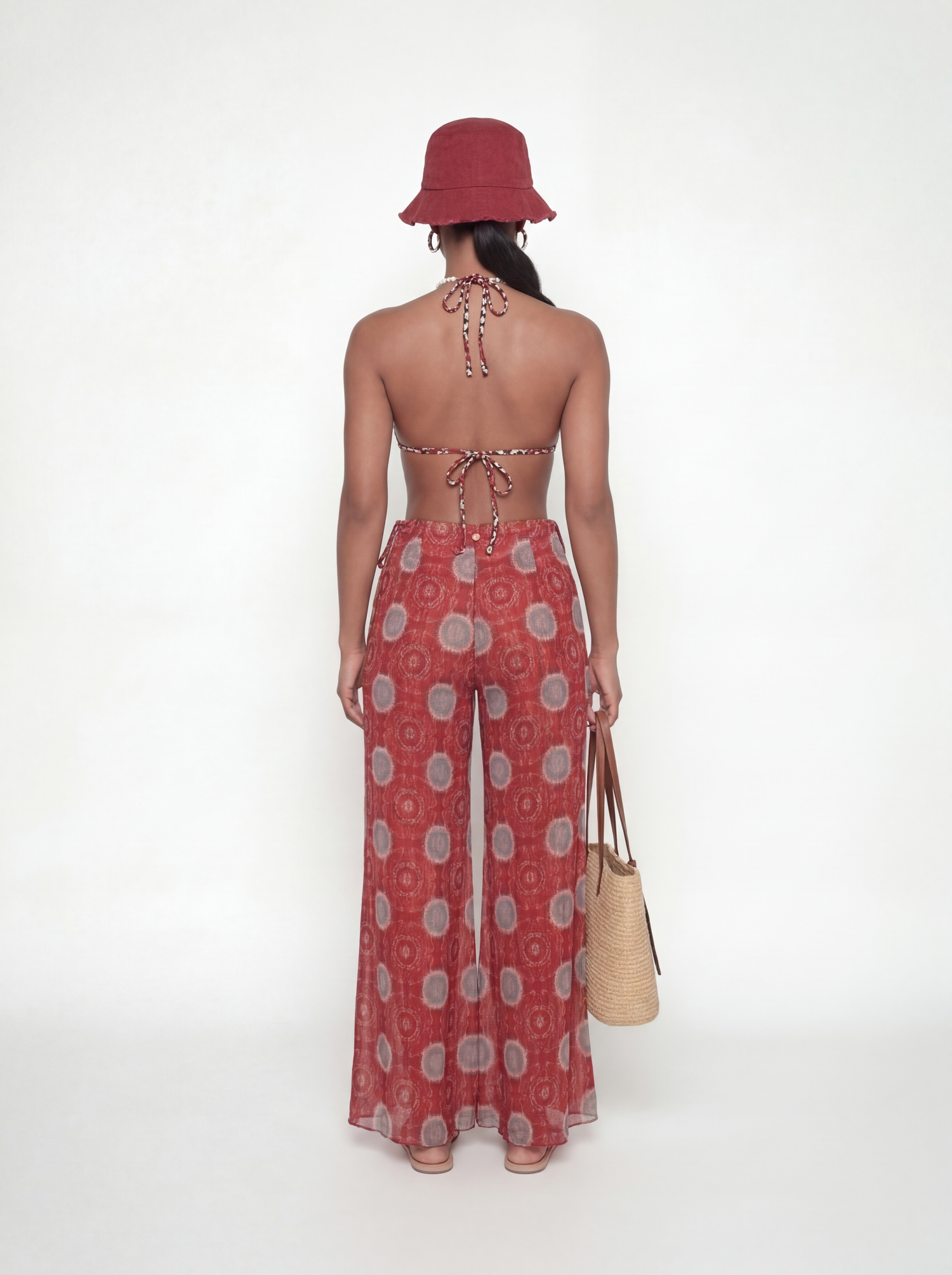 Woman wearing a red patterned dress and hat on a white background