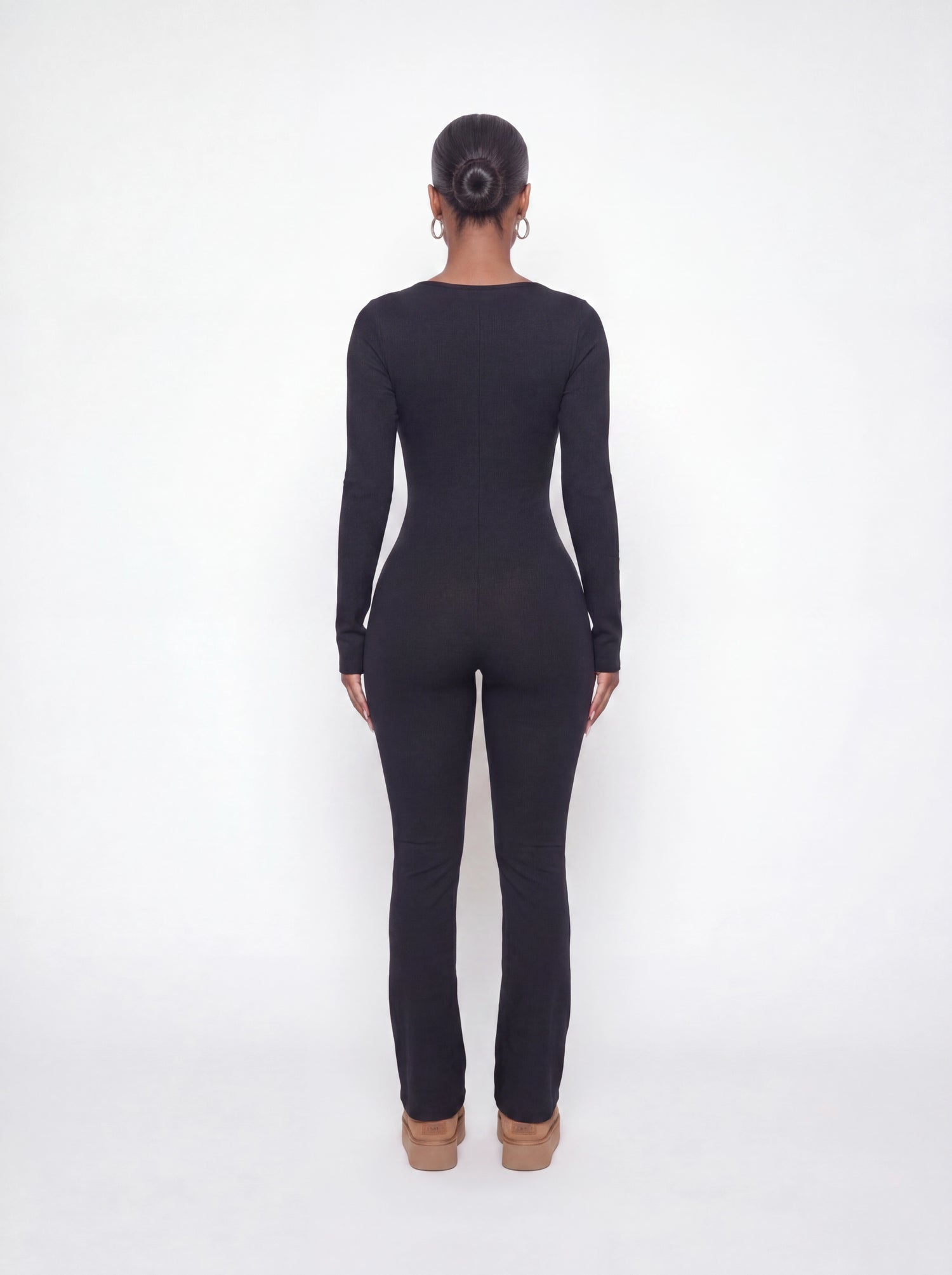 Back view of a black ribbed long sleeve jumpsuit featuring a body-contouring fit, full-length legs, and soft stretchy ribbed fabric.