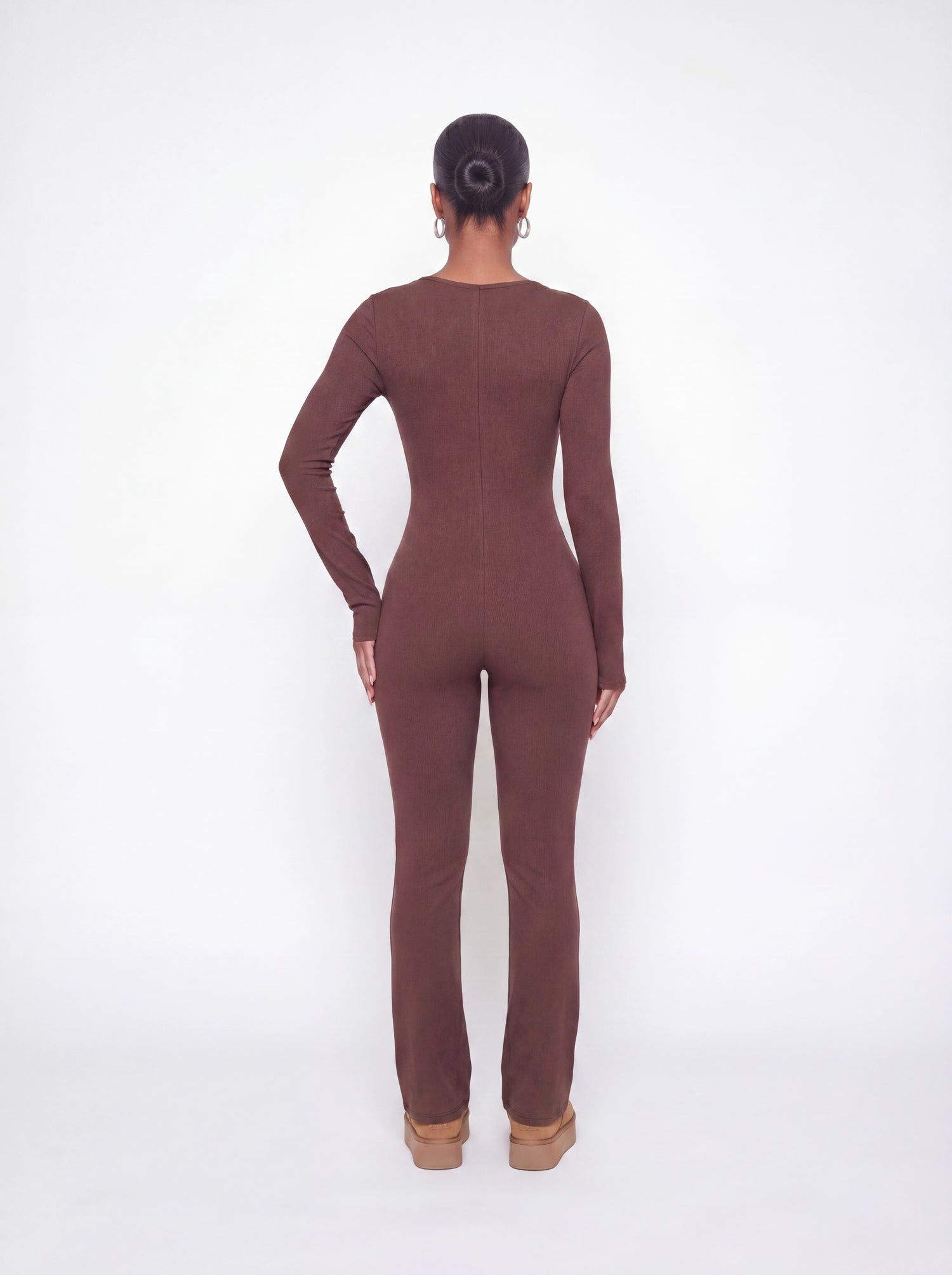 Back view of a brown ribbed long sleeve jumpsuit featuring a body-contouring fit, full-length legs, and soft stretchy ribbed fabric.
