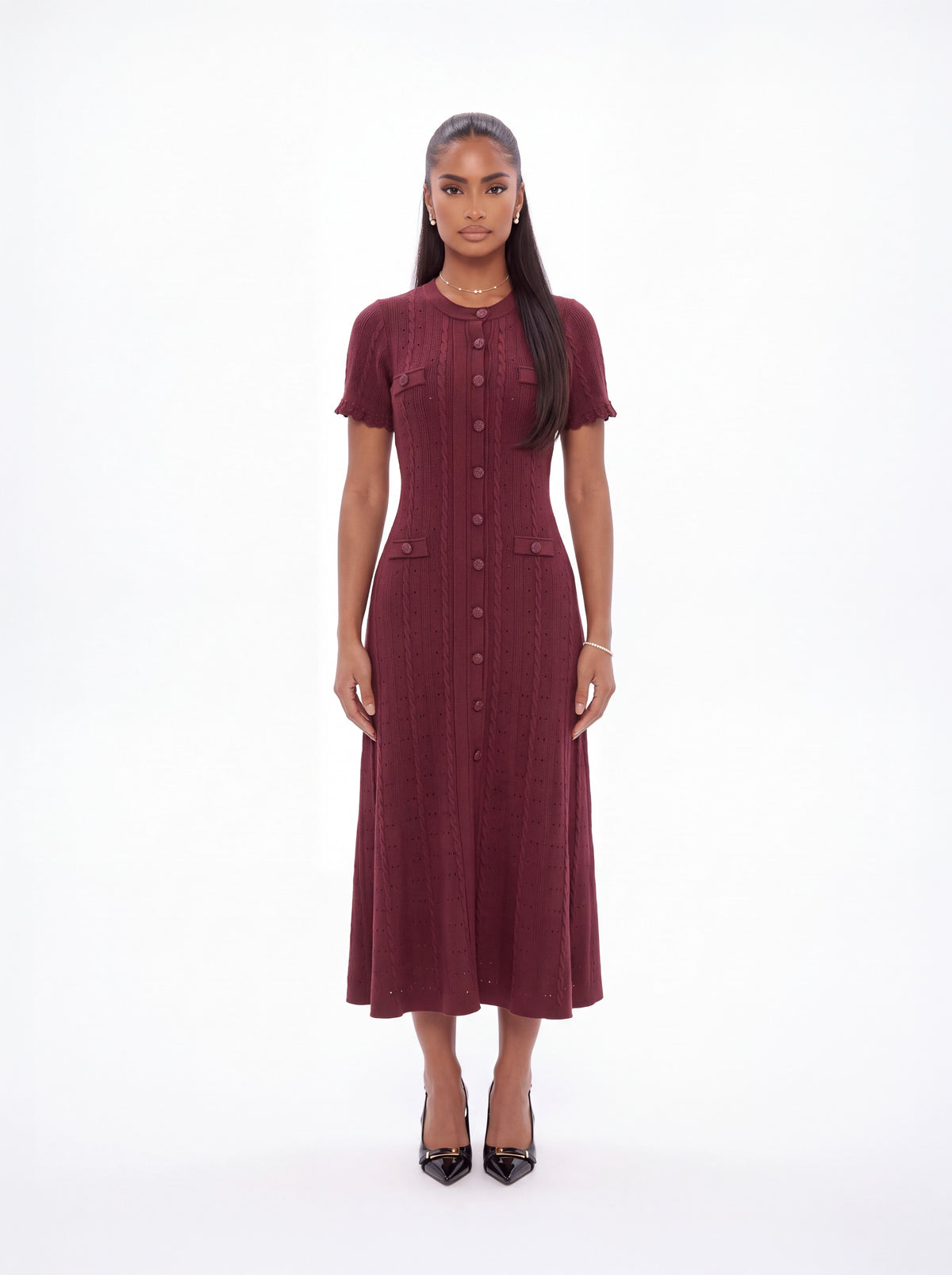 A woman modeling a short-sleeved, button-front midi dress in a deep burgundy color, standing against a seamless white studio background.