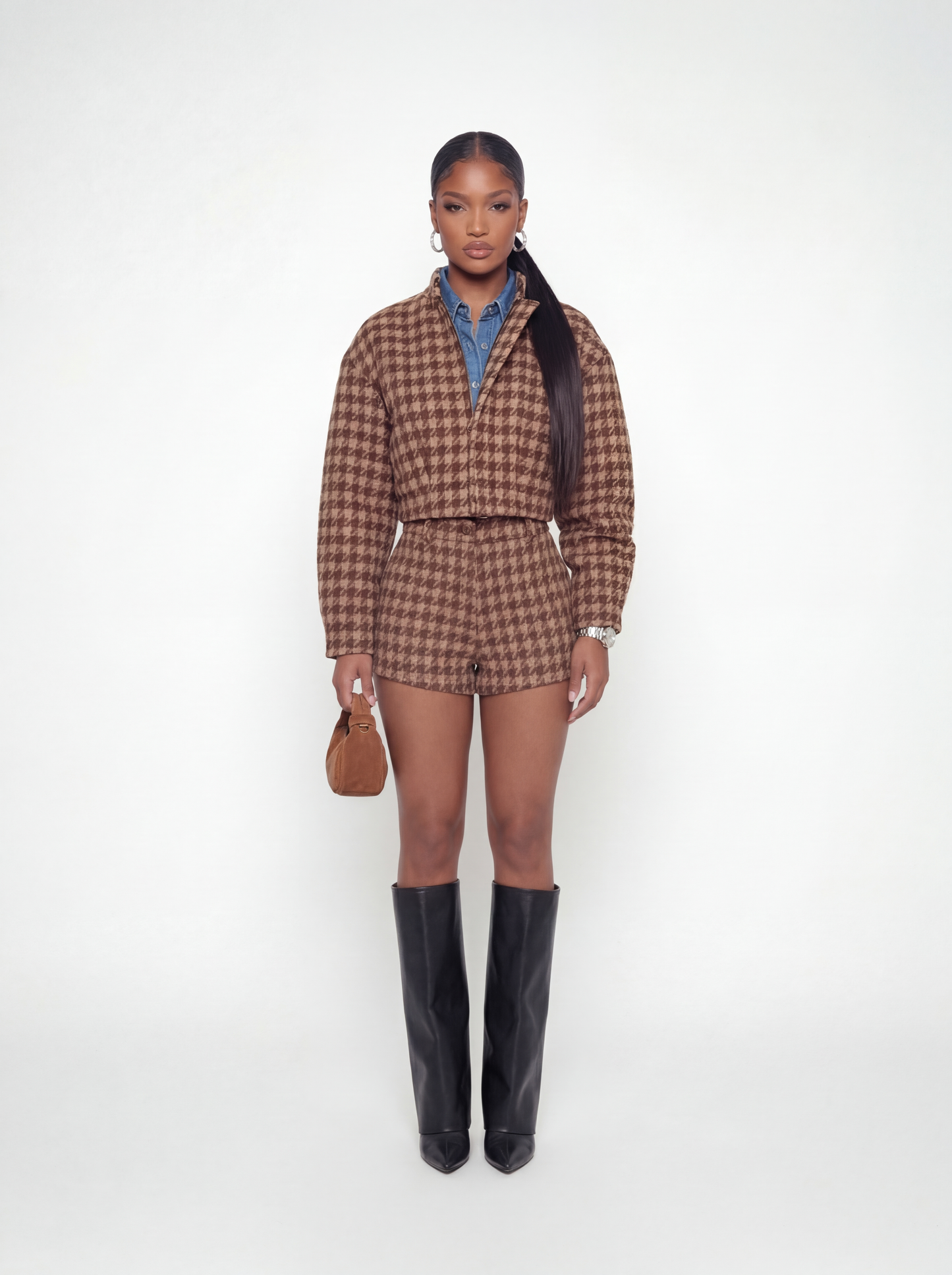 Woman wearing a brown checkered outfit with black boots on a white background