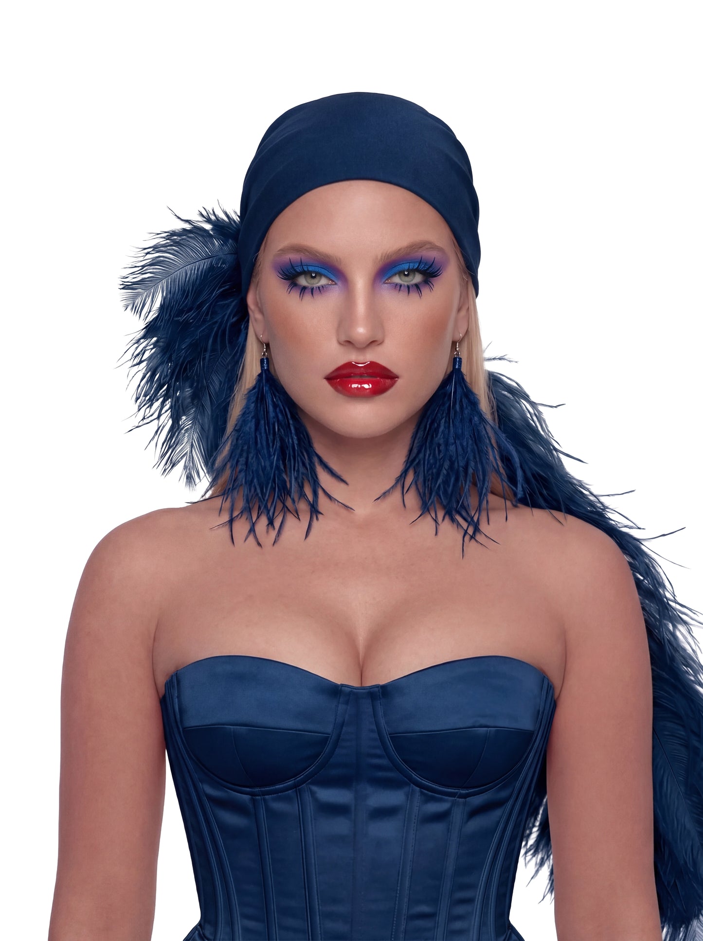 A woman modeling a dark blue feathered headband and matching feathered headpiece with a strapless dark blue satin corset top against a plain white background.