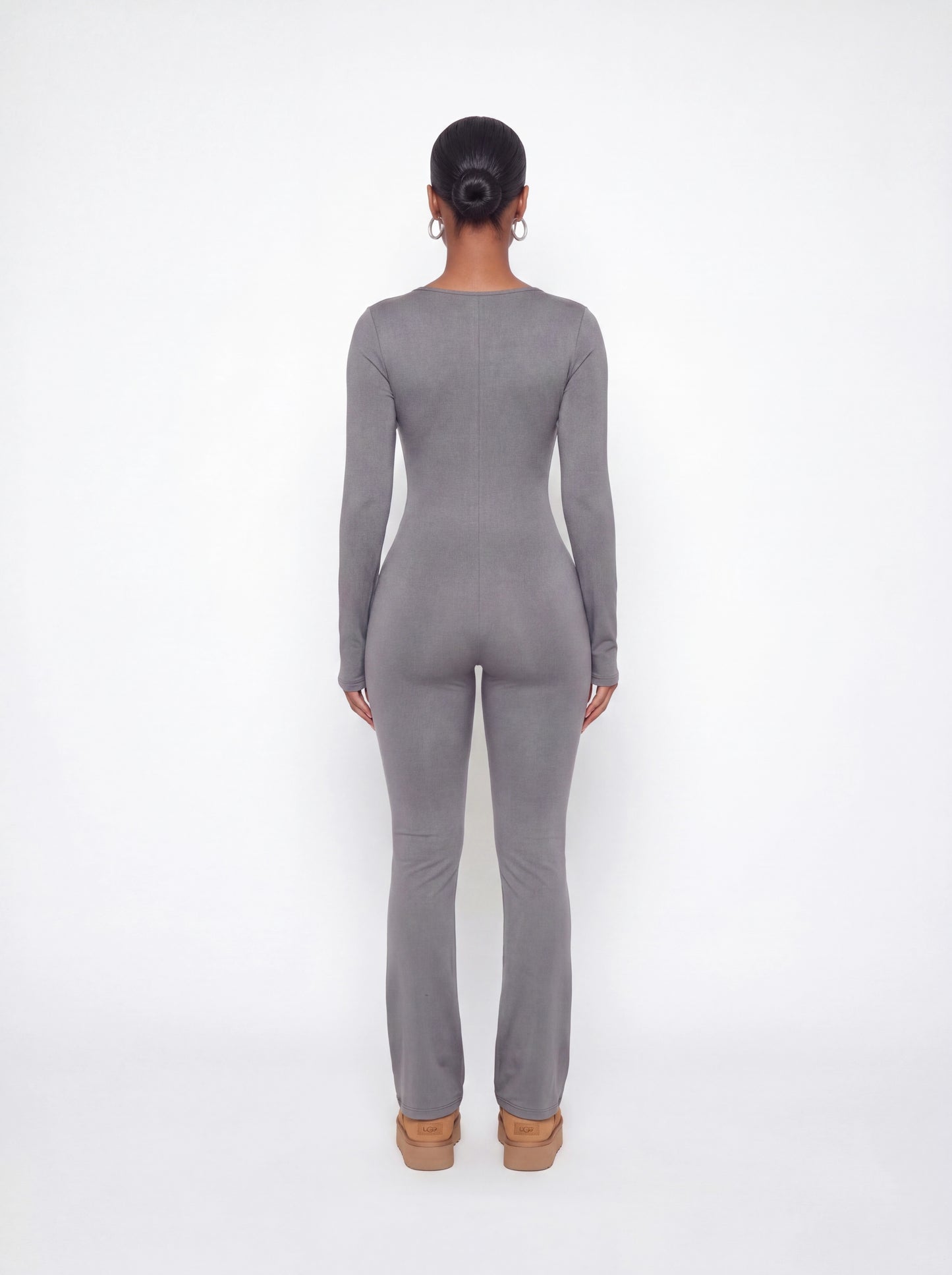 Back view of a grey ribbed long sleeve jumpsuit featuring a body-contouring fit, full-length legs, and soft stretchy ribbed fabric.