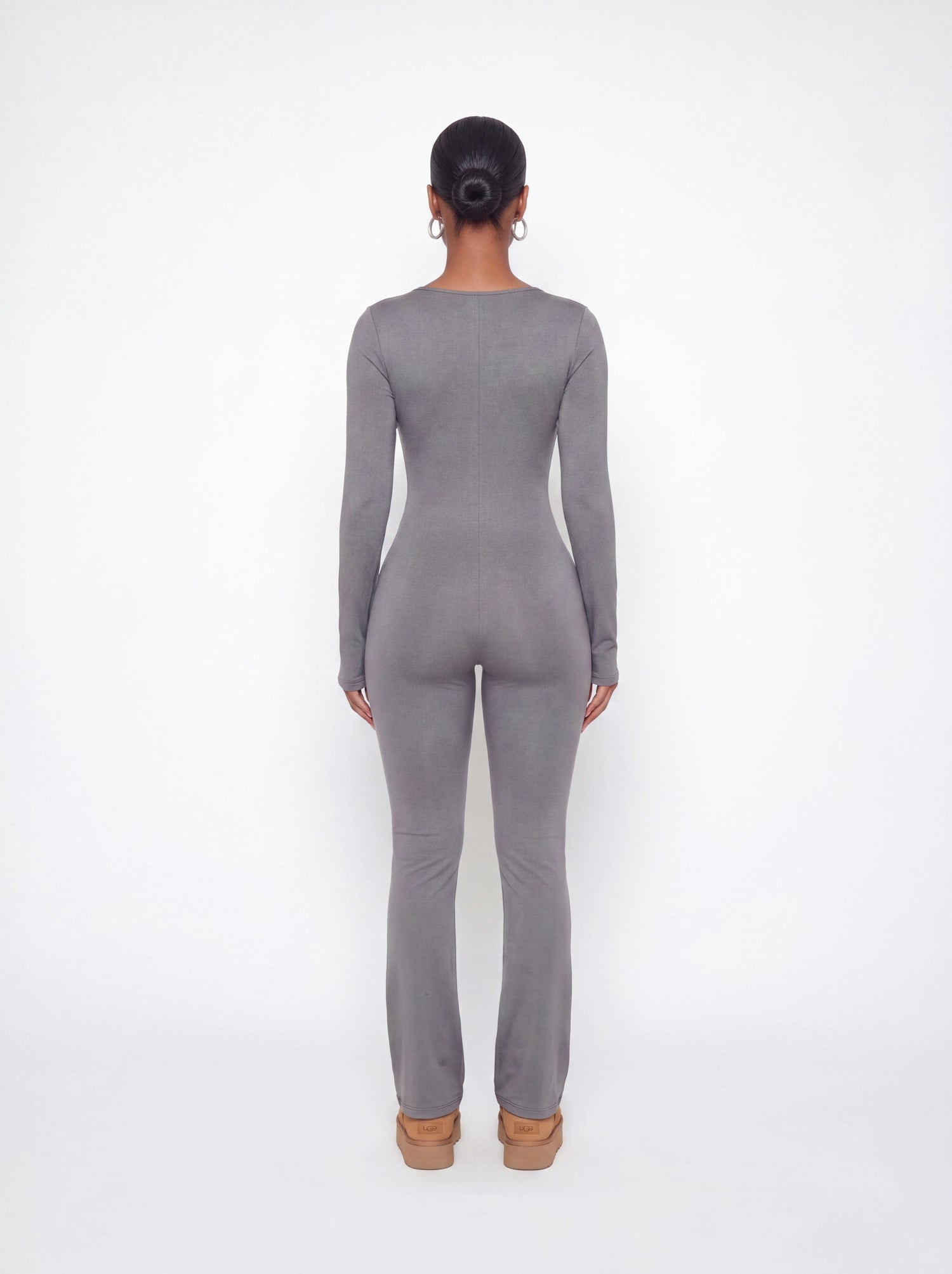 Back view of a grey ribbed long sleeve jumpsuit featuring a body-contouring fit, full-length legs, and soft stretchy ribbed fabric.