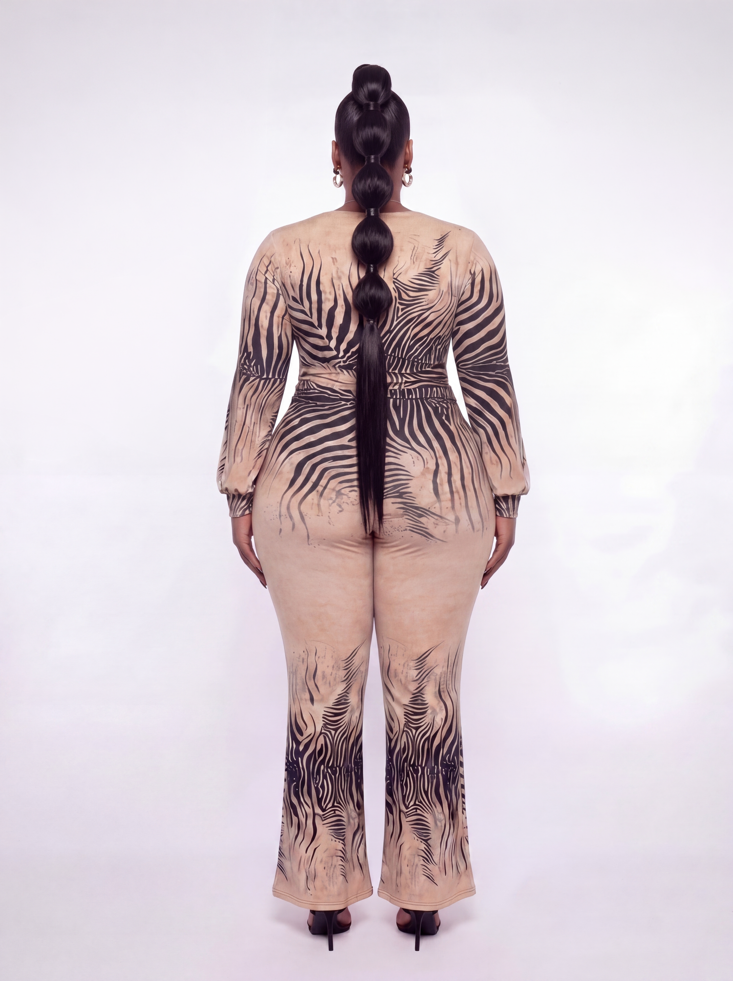 Person wearing a beige outfit with black feather-like patterns on a white background