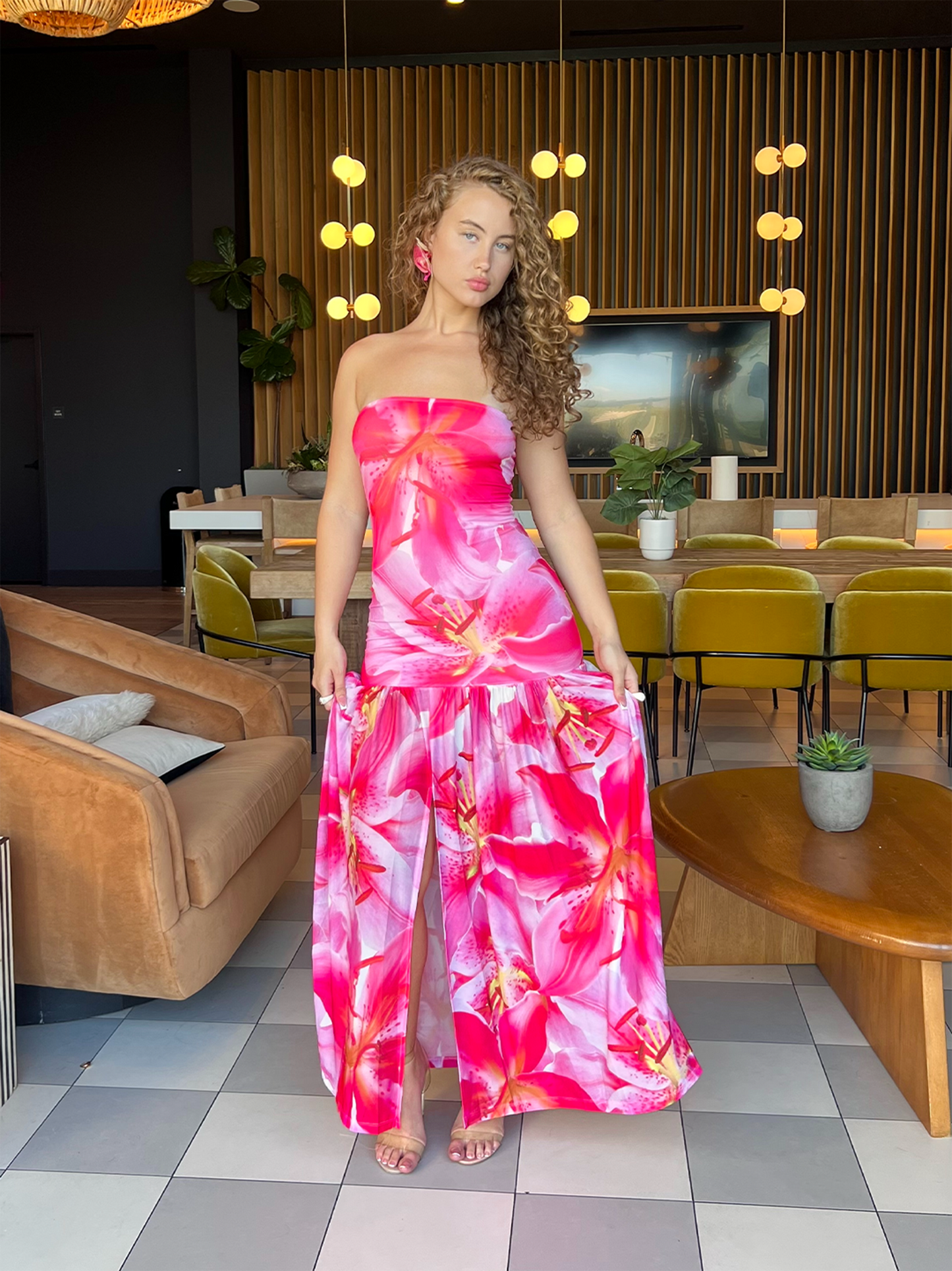 Model wearing a strapless pink floral maxi dress with a fitted top and flowy skirt, styled for a vacation or summer look.